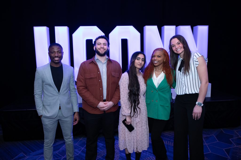 Scholarship recipients behind a UConn sign at the annual scholarship celebration held at the UConn Alumni Center